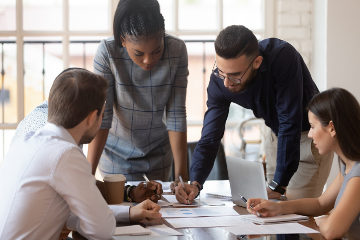 Focused multiracial corporate business team people brainstorm on paperwork Focused multiracial corporate business team people brainstorm on marketing plan financial report gather at office table meeting, diverse serious colleagues group discuss paperwork engaged in teamwork